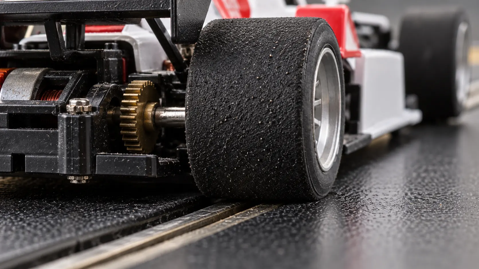Pneu traseiro de carro de autorama em contato com o trilho da pista.